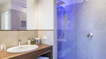 A modern bathroom with a wooden vanity, a white sink, and a glass-enclosed shower area.