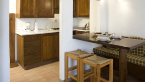 A kitchen with wooden cabinets, a white countertop, and a dining area with a bench and table. - Agriturismo Colognole (Pontassieve)