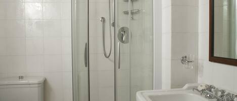 A bathroom with a glass-enclosed shower, a white sink, and a toilet.