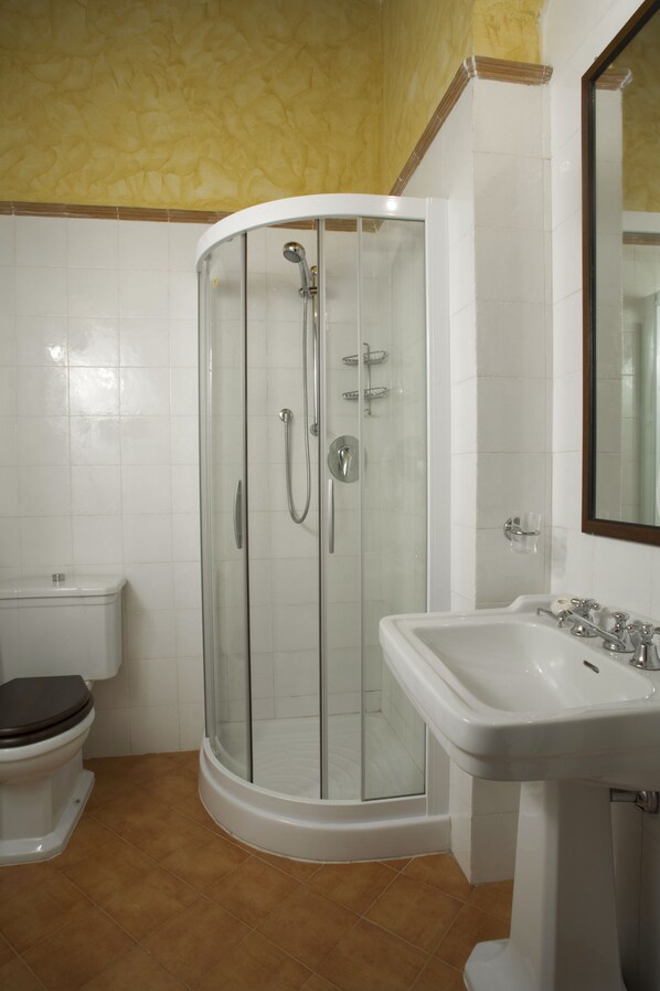 Une salle de bain avec une douche à parois de verre, un lavabo blanc et des toilettes.