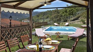An outdoor patio with a pool, wooden furniture, and a table set for a meal. - Agriturismo Colognole (Pontassieve)