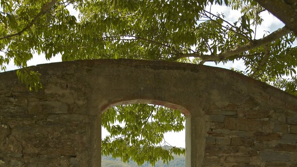 A stone archway leading to a pool area with two lounge chairs. - Agriturismo Colognole (Pontassieve)