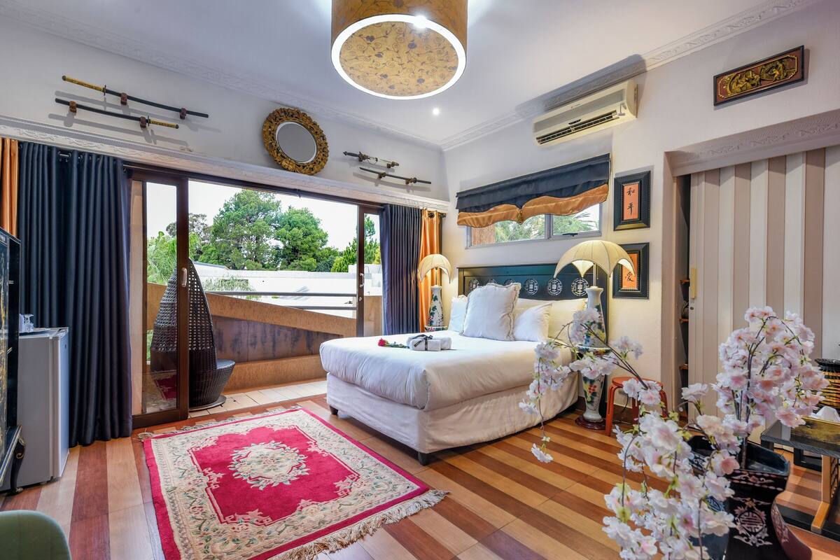 Habitación de hotel con una cama, un tapete de diseño rojo y blanco, un aplique de techo y vistas a través del ventanal.