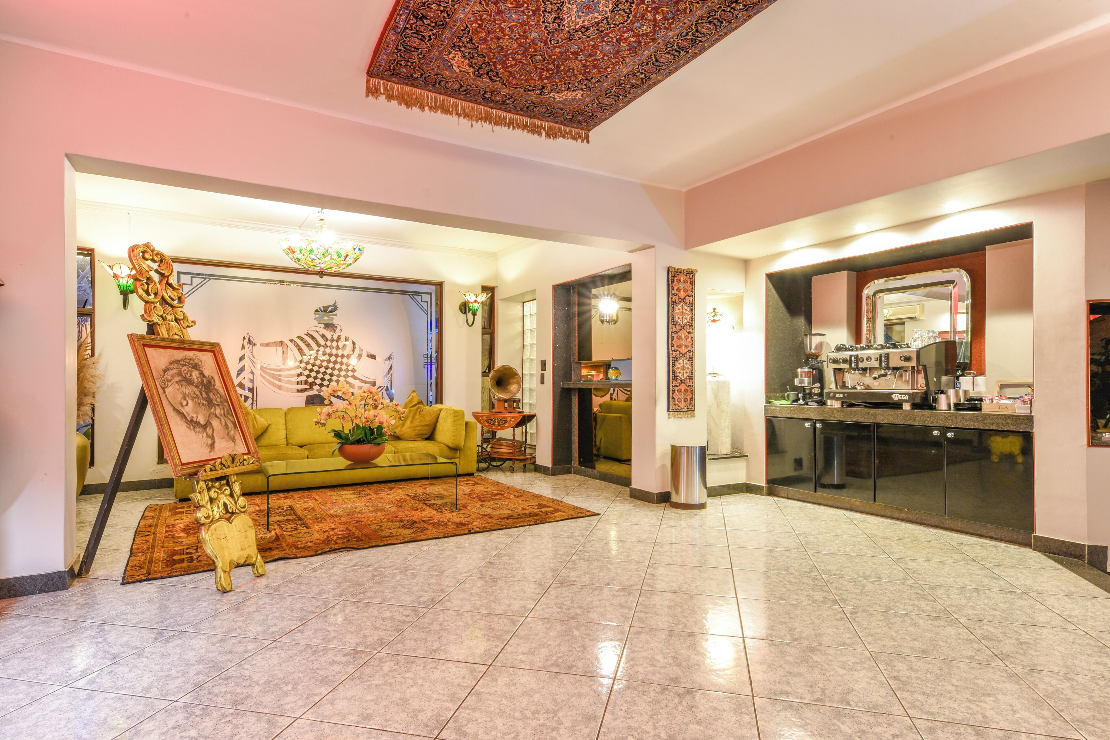A spacious living room with a green sofa, a decorative rug, and a chandelier.