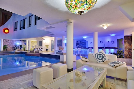 Una piscina al aire libre, sombrillas, sillones reclinables de piscina