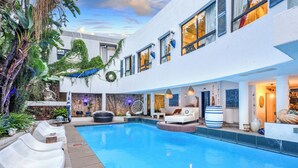 A modern pool area with lounge chairs, a stone fountain, and a well-maintained garden. - Villa Simonne (Johannesburg)