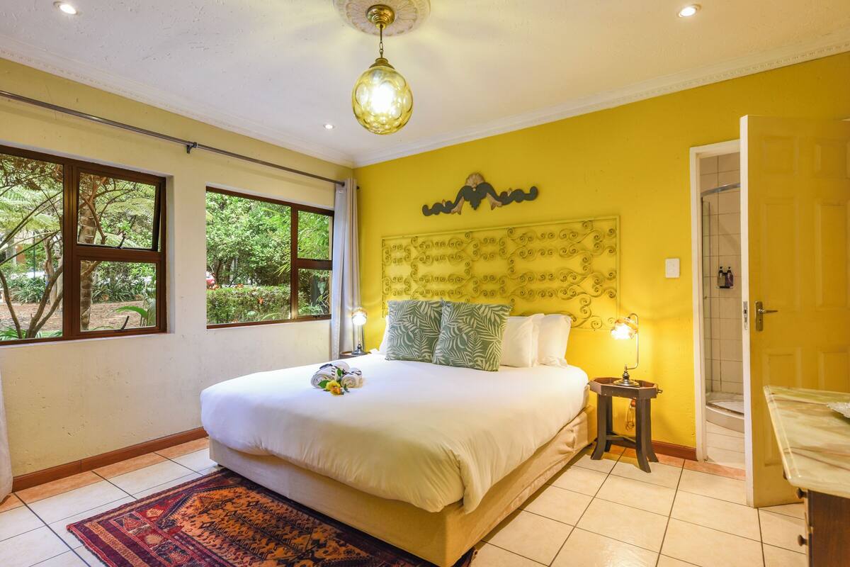 Un dormitorio con cama, mesita de noche, cabecero fijado a la pared y ventana.