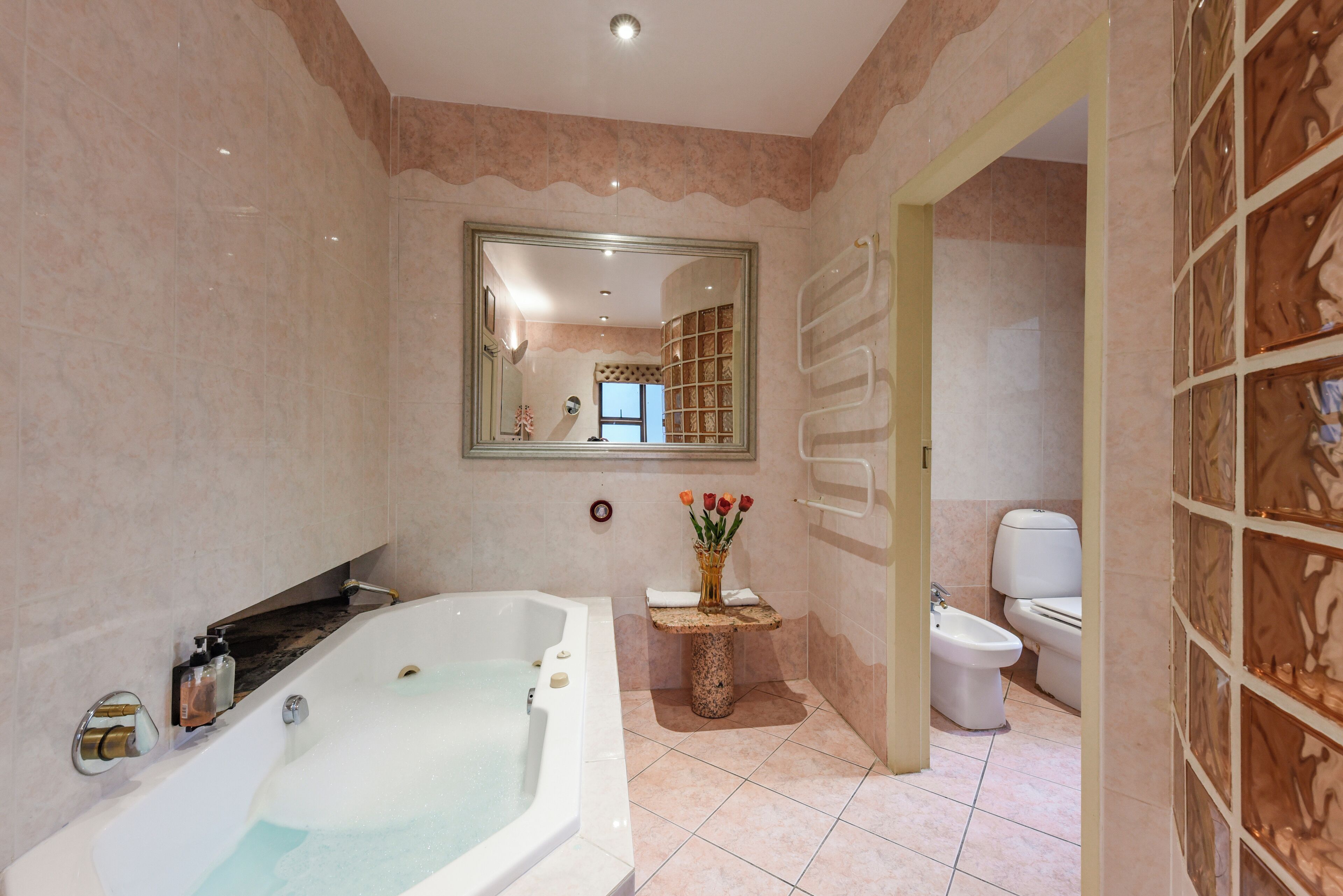 Une salle de bain avec une grande baignoire, des toilettes et un meuble-lavabo avec un miroir.