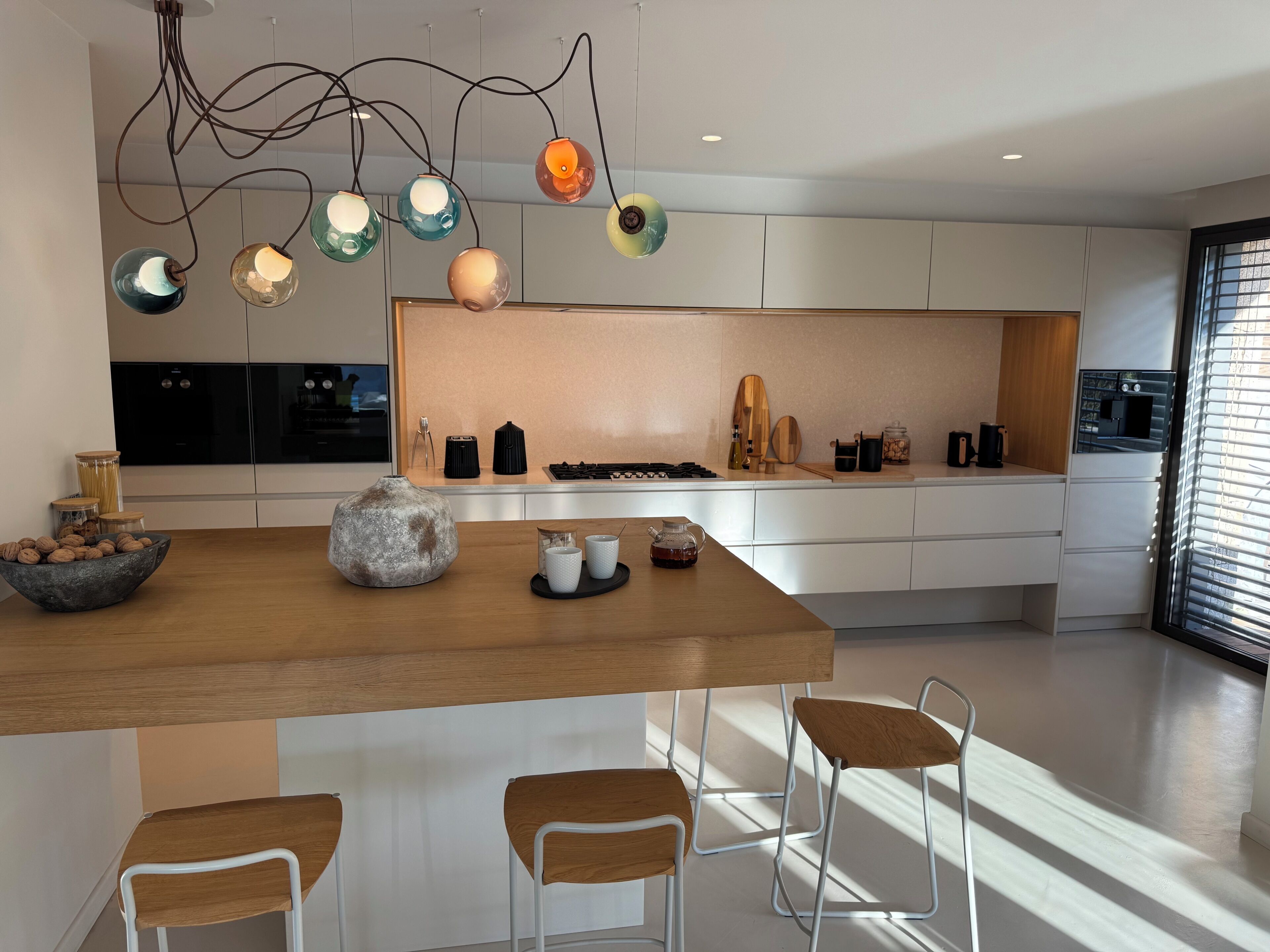 Een moderne keuken met een centraal eiland, witte kasten en hanglampen.