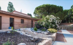 A wooden cabin with a stone retaining wall and a variety of flowering plants. - Bartaccia Hotel (Propriano)