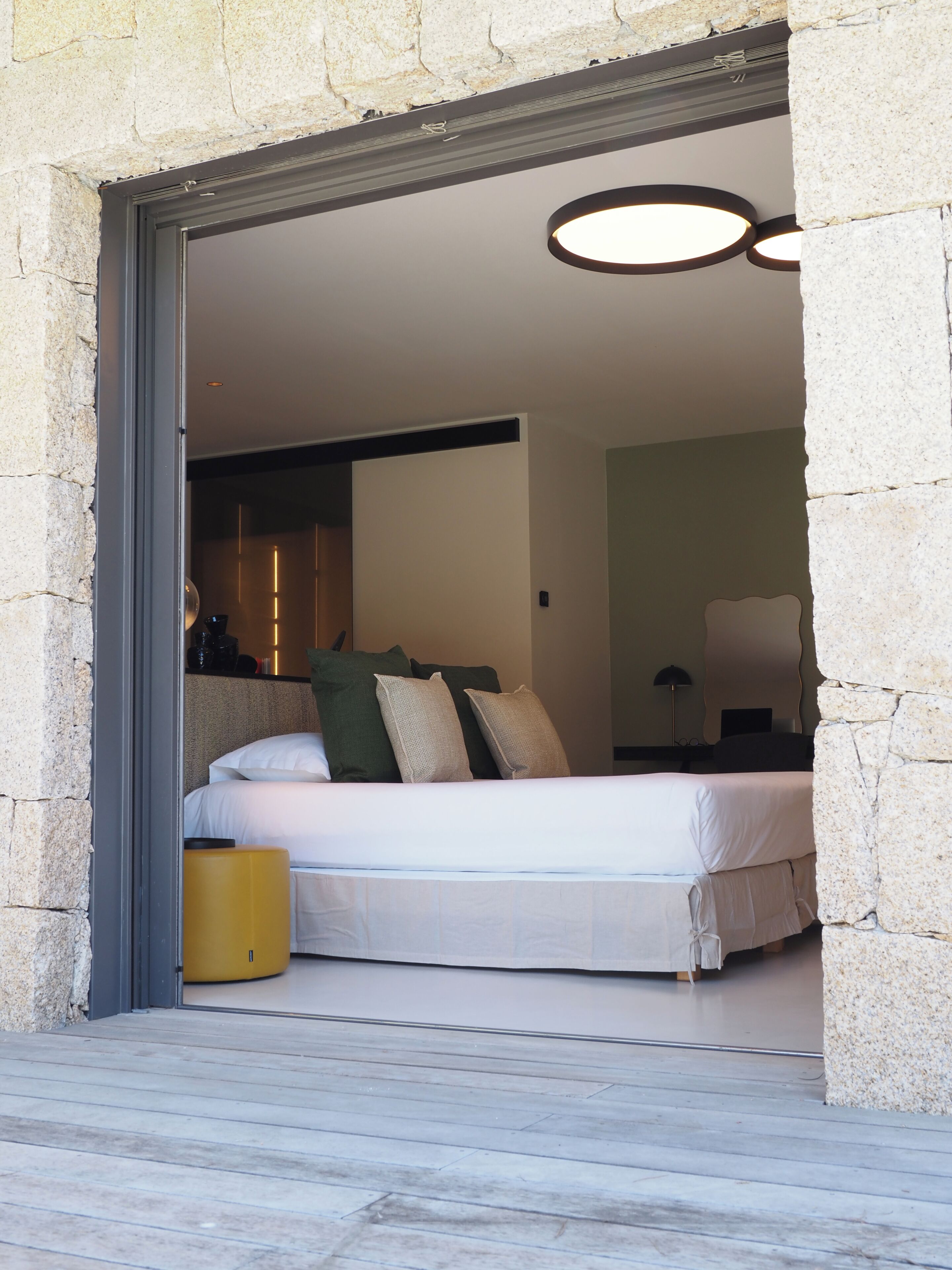 A bedroom with a bed, pillows, a bedside table, and a lamp.
