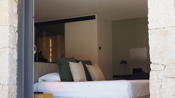 A bedroom with a bed, pillows, a bedside table, and a lamp.