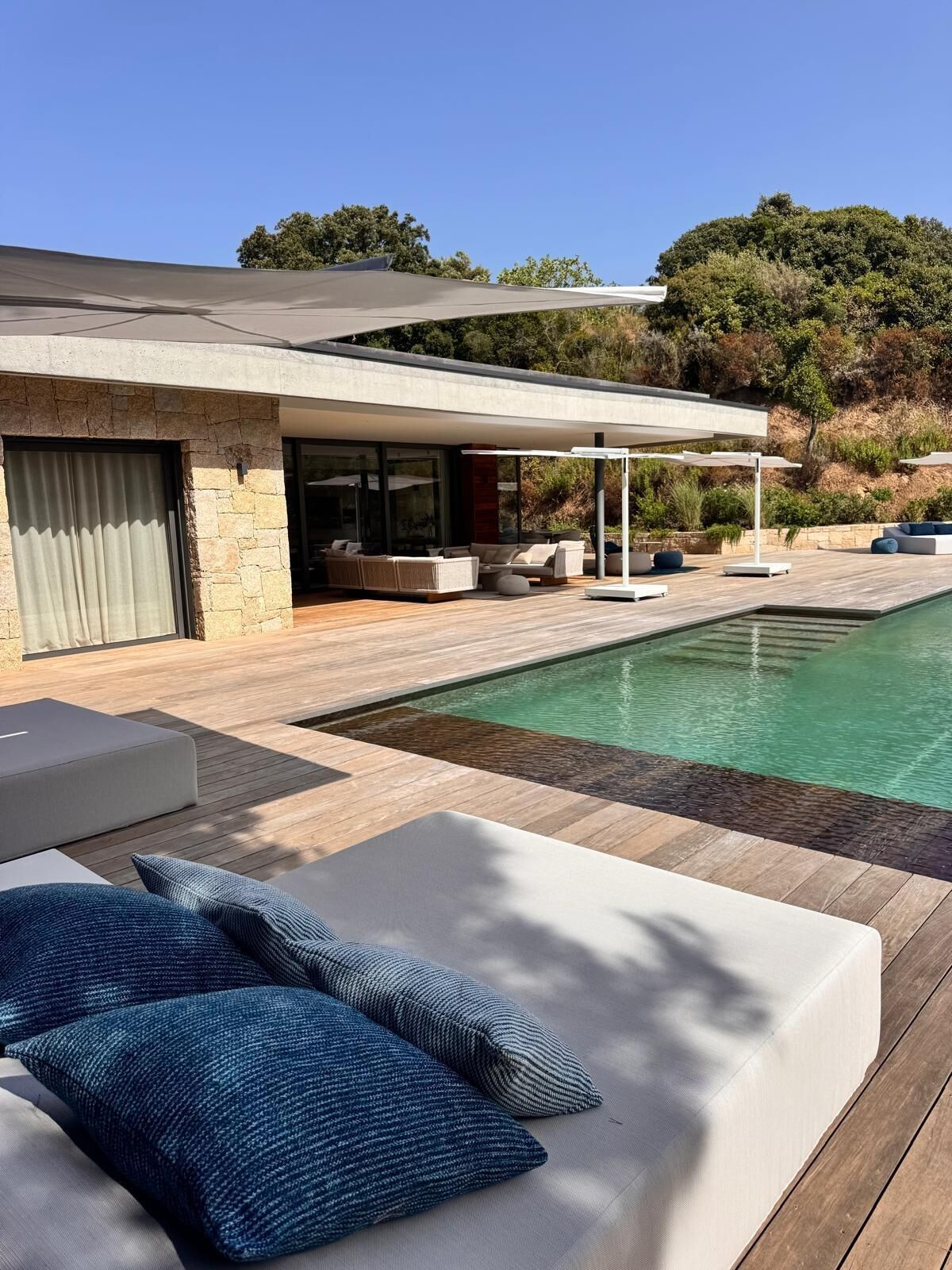Een modern huis met zwembad, terras en uitzicht op het omliggende landschap.