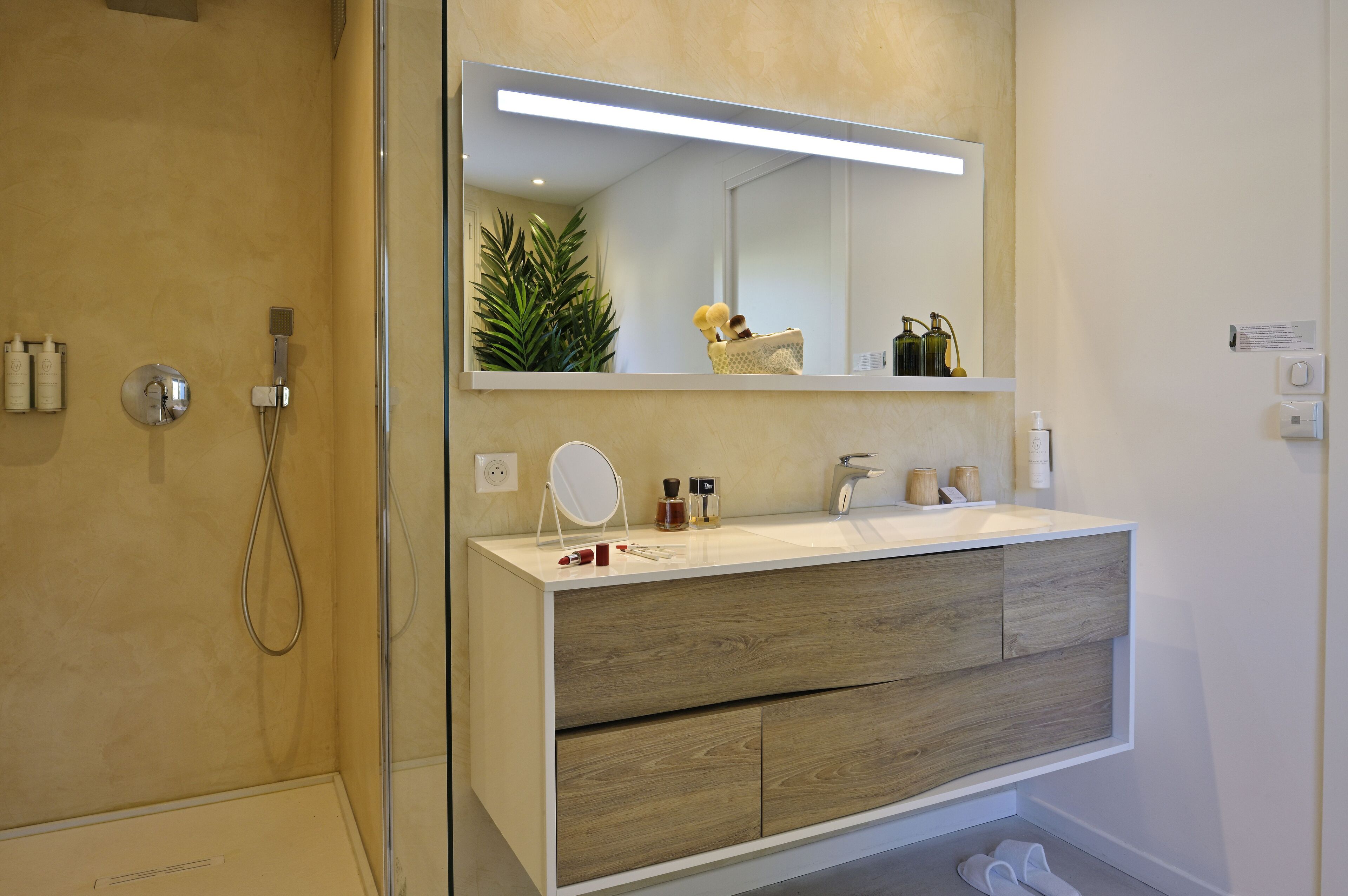 A modern bathroom with a large mirror, wooden vanity, and a shower area.