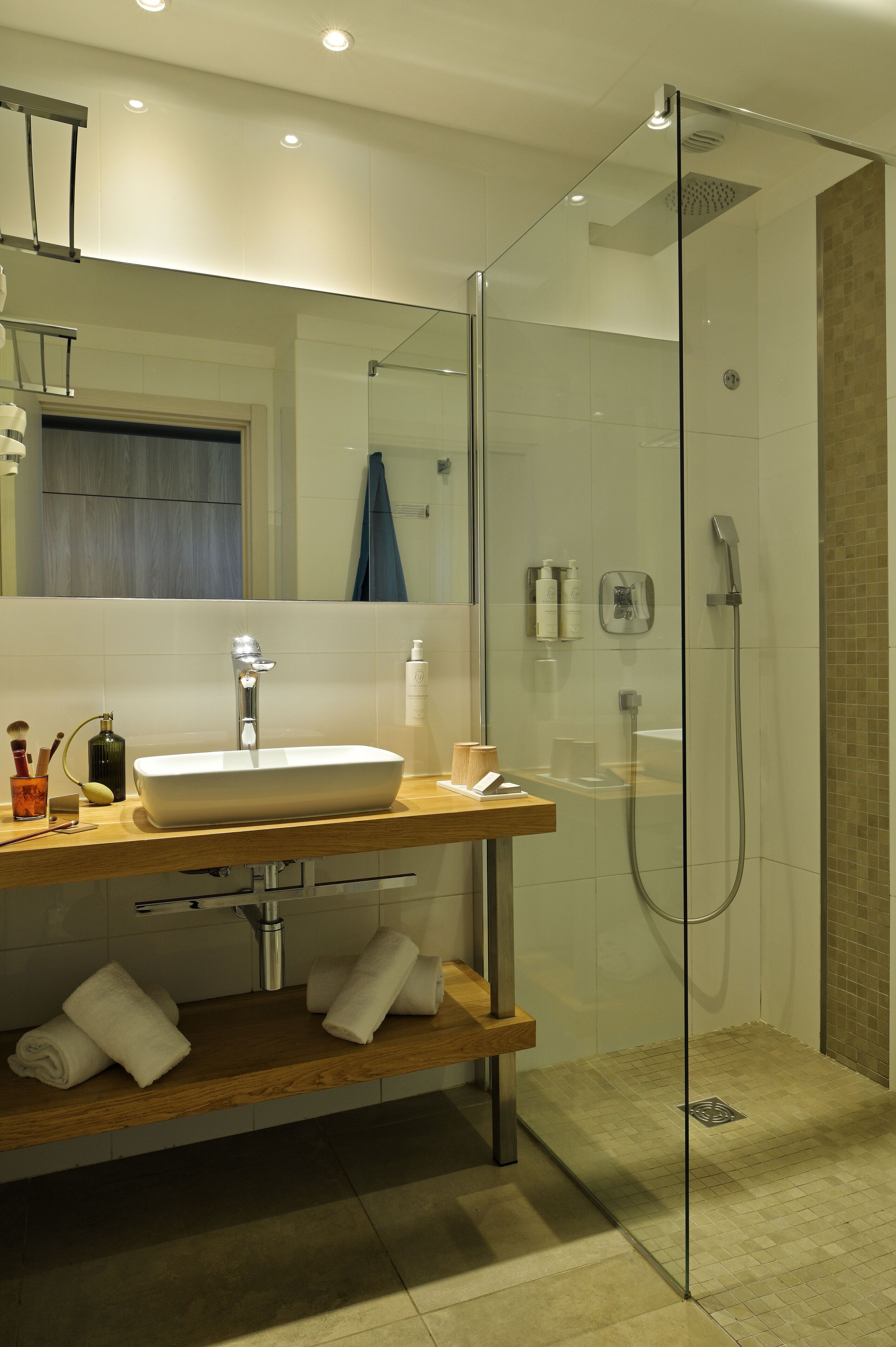 A modern bathroom with a glass-enclosed shower, a wooden vanity, and a large mirror.