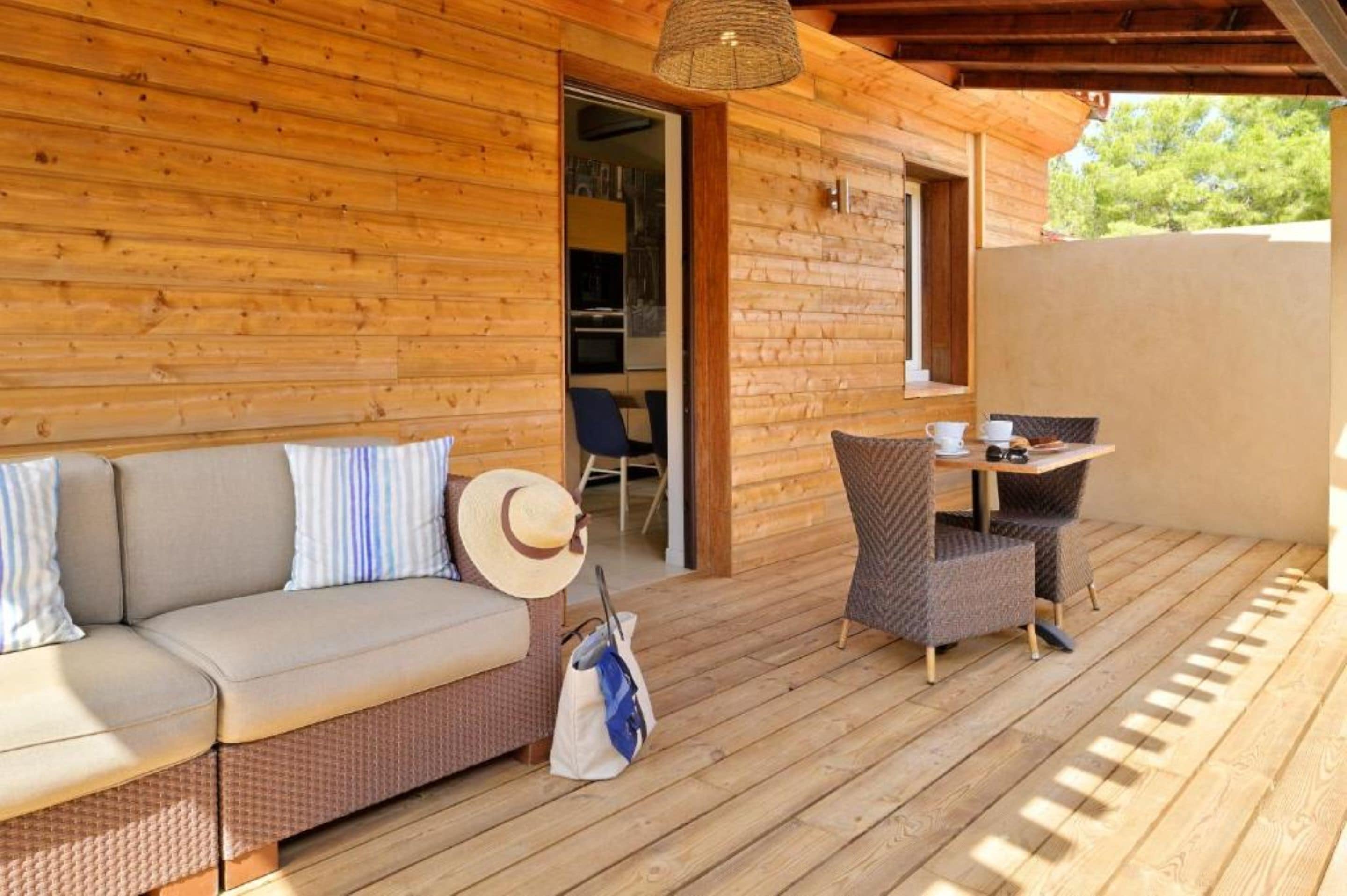 Terraza de madera con sofá, sillas, una mesa y una lámpara colgante.