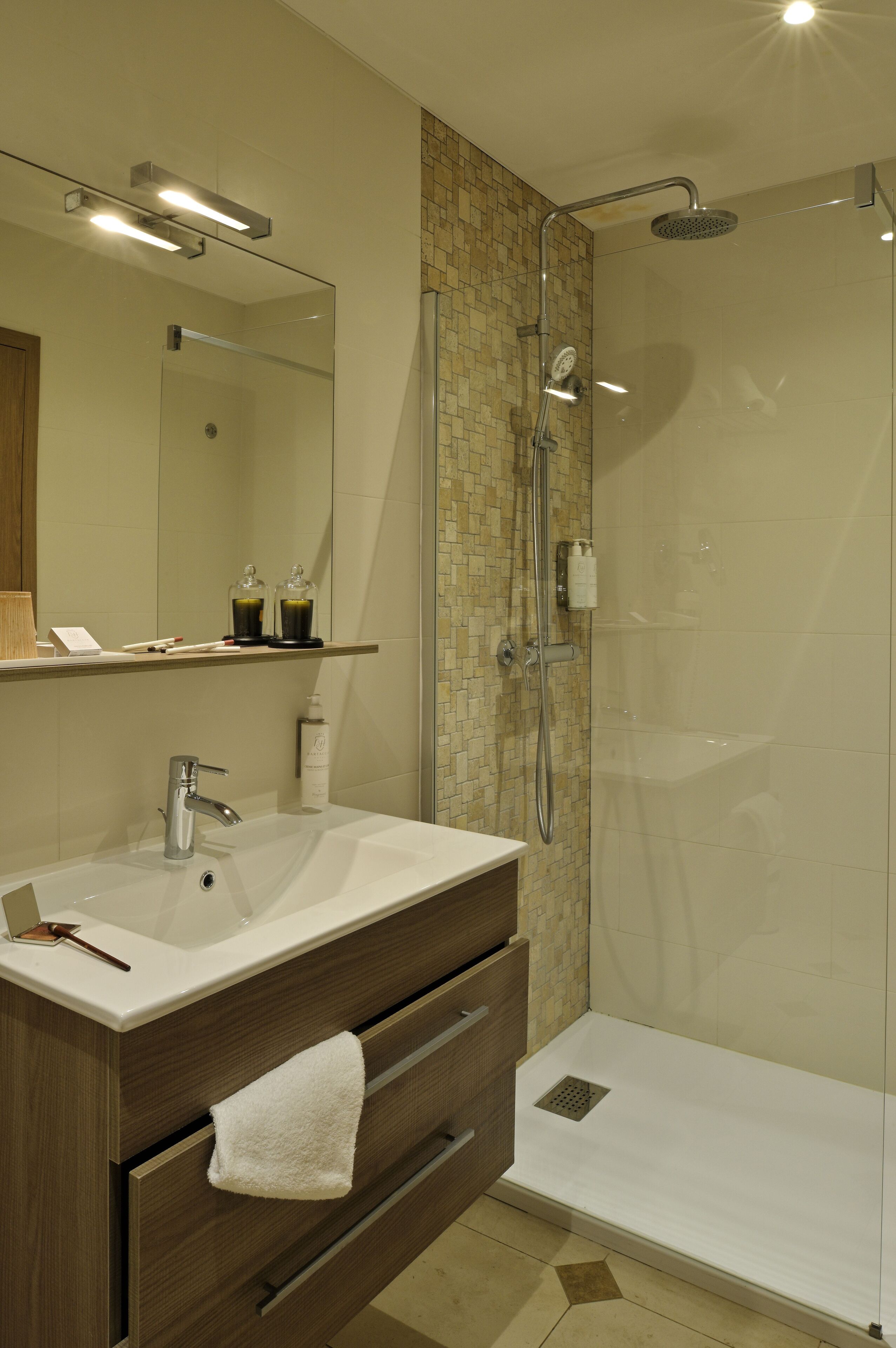 A modern bathroom with a glass-enclosed shower, a white sink, and a mirror above it.