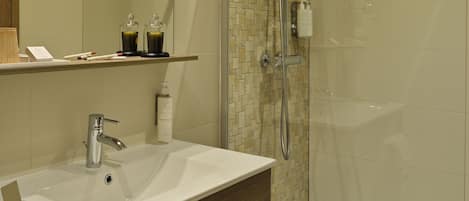 A modern bathroom with a glass-enclosed shower, a white sink, and a mirror above it.