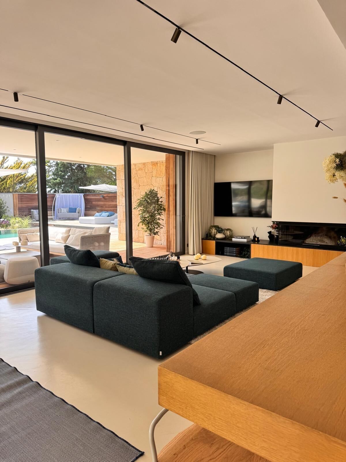 Una sala de estar moderna con un conjunto de sofás, una mesa de comedor y un televisor montado en la pared.