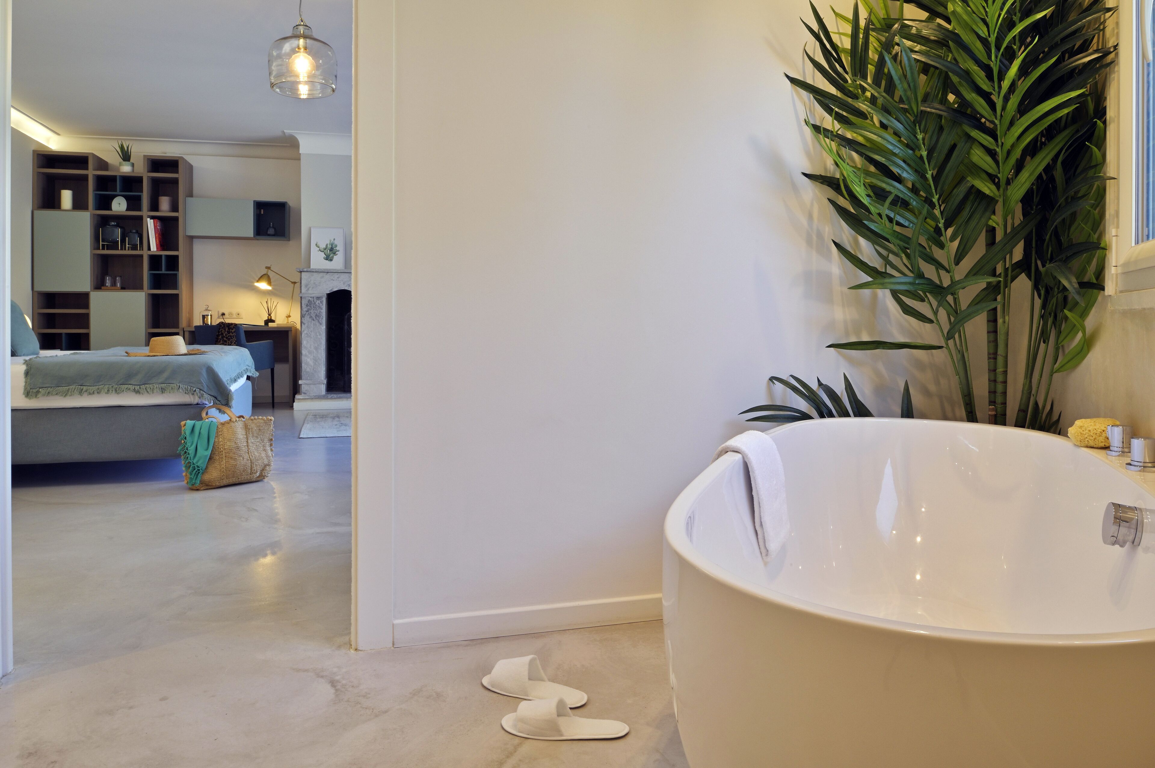 Ein modernes Badezimmer mit einer freistehenden Badewanne, einer großen Topfpflanze und einem minimalistischen Design.