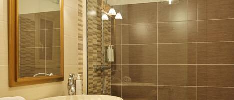 Une salle de bain moderne avec un meuble-lavabo en bois, un grand miroir et une douche à parois de verre.