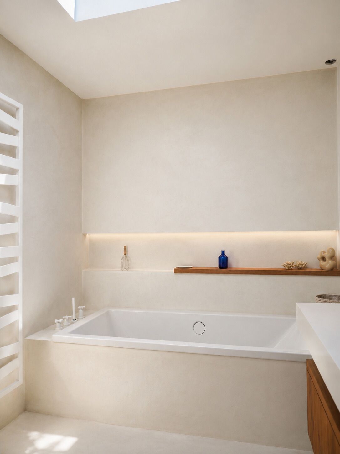 Un baño moderno con una bañera independiente, un estante de madera con adornos y un tragaluz.