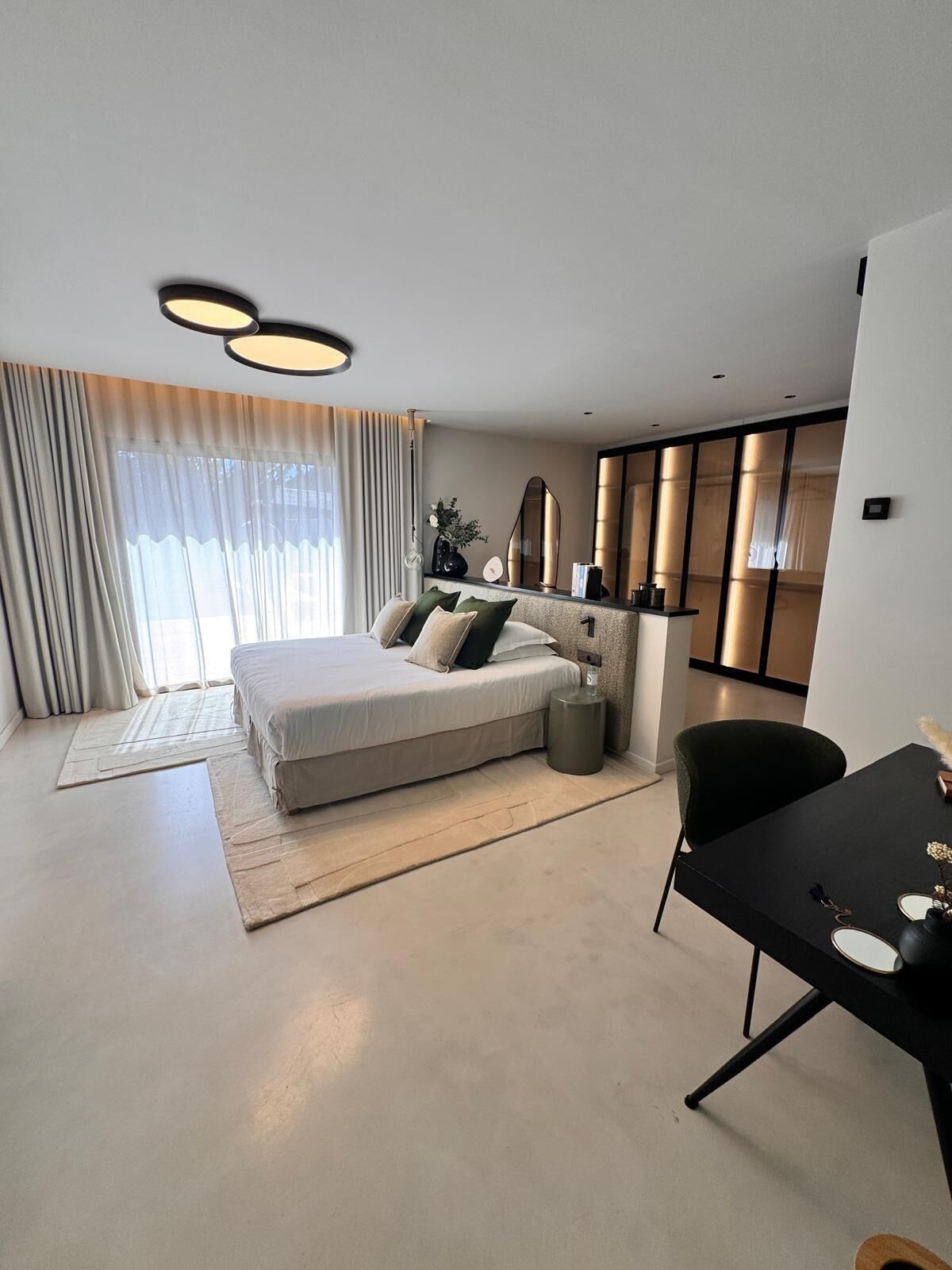A modern bedroom with a bed, bedside tables, a desk, and a chair.