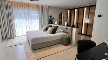 A modern bedroom with a bed, bedside tables, a desk, and a chair.
