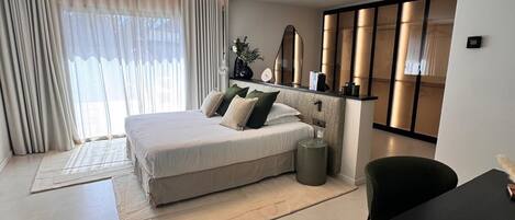 Une chambre à coucher moderne avec un lit, des tables de chevet, un bureau et une chaise.