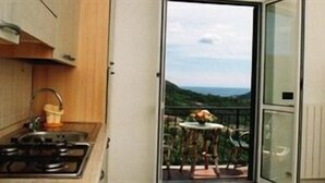Eine Küche mit Gasherd und Blick auf einen Balkon mit Tisch und Stühlen.