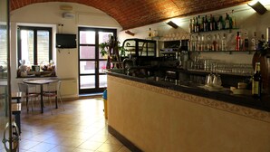 Eine Bar mit Backstein Decke, Fliesenboden und einer Theke mit verschiedenen Flaschen und Gläsern.