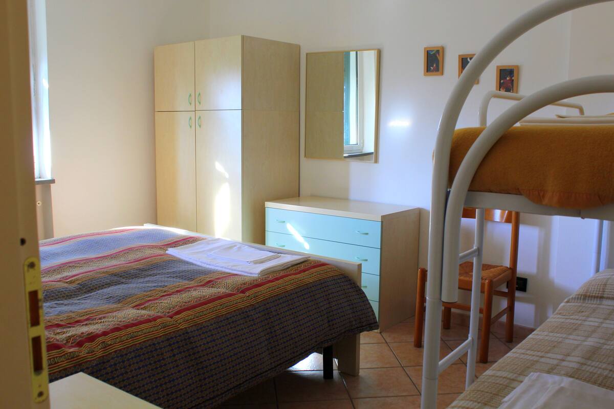 Una camera da letto con un letto a castello, un letto singolo, un armadio, una scrivania e una sedia.