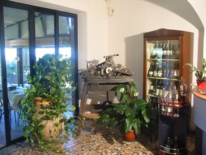 Een kamer met betegelde vloer, een vintage typmachine, een wijnrek en diverse potplanten.