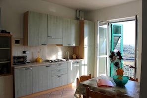 A kitchen with a dining area, a view through the window, and a table with a vase.