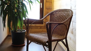 A corner room with a wicker chair, a potted plant, and wooden walls. - Albergo Da Cecilia (Bognanco)