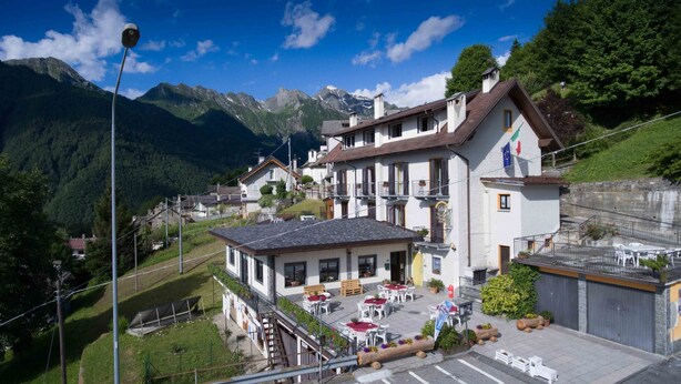 A mountain village with a restaurant featuring outdoor seating and a view of the surrounding mountains. - Albergo Da Cecilia (Bognanco)