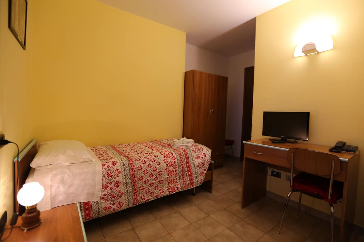 A room with a bed, a desk, a chair, a television, and a wardrobe.