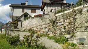 A traditional stone building with a steep stone staircase leading to a wooden deck. - Albergo Da Cecilia (Bognanco)