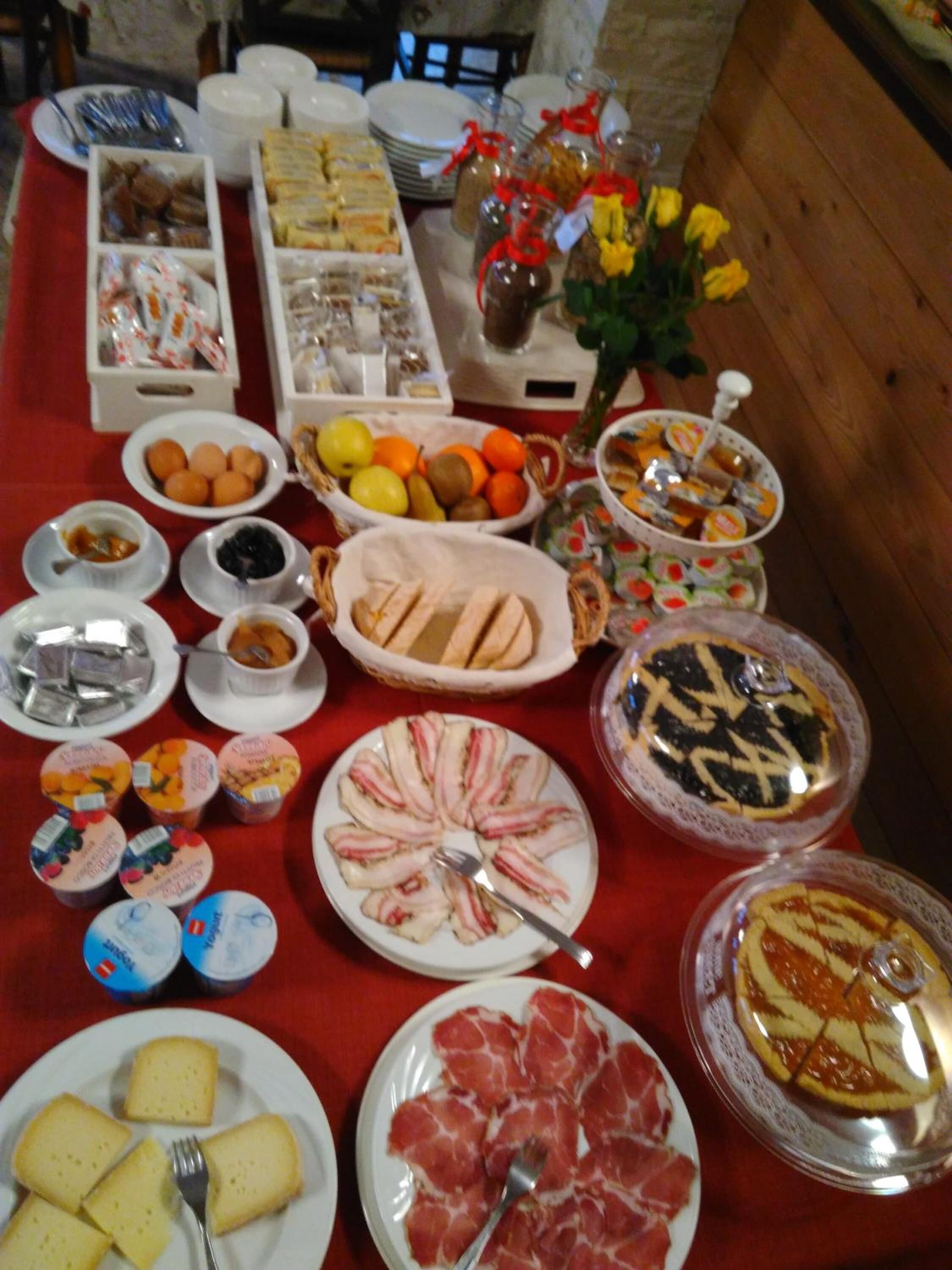 Une table de buffet proposant une variété d’aliments, notamment des fruits, des pâtisseries et des viandes.
