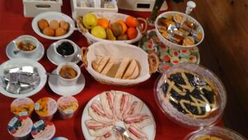 Une table de buffet proposant une variété d’aliments, notamment des fruits, des pâtisseries et des viandes.