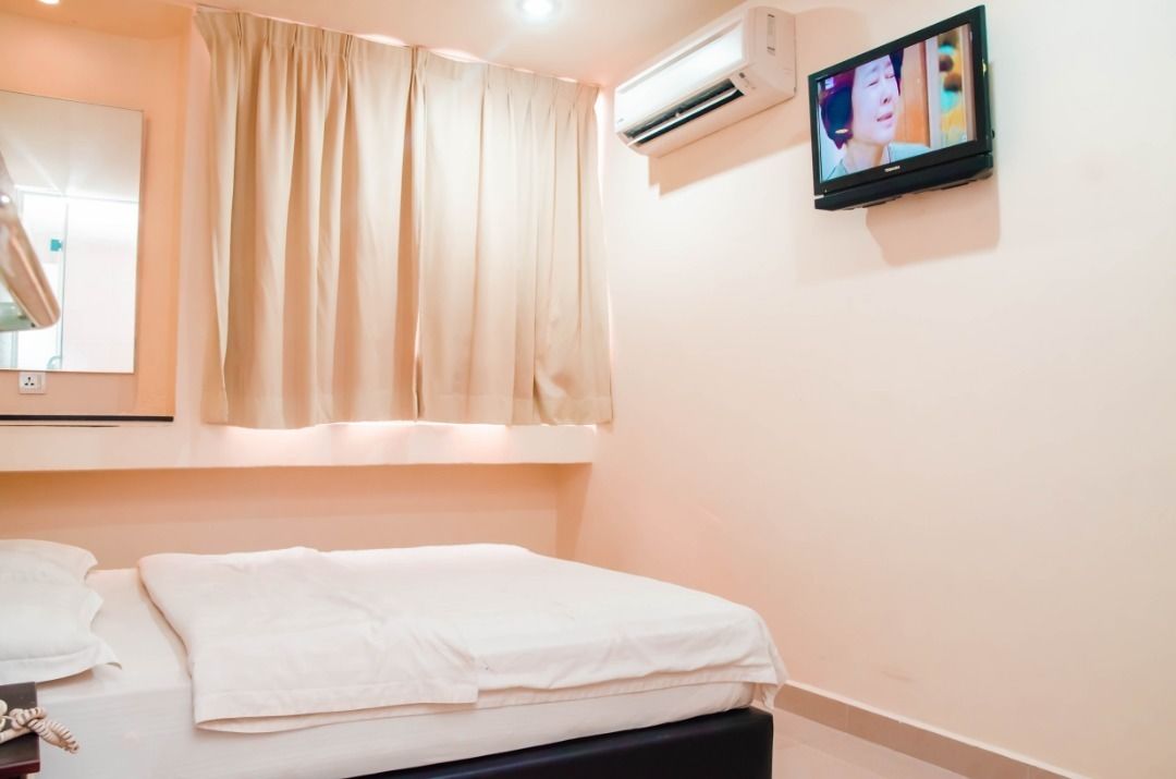 Une chambre d’hôtel équipée d’un lit, d’un téléviseur fixé au mur et d’un appareil de climatisation.