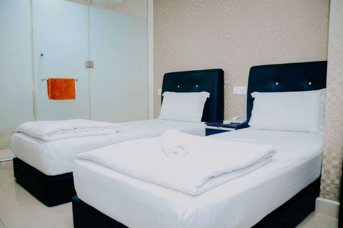 A hotel room with two beds, a bathroom, and a shower area.