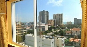 Blick aus einem Fenster auf eine Skyline mit mehreren Hochhäusern und blauem Himmel.