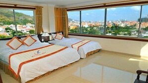 A hotel room with two beds, a large window with a city view, and a small table. - Binh Phuong Hotel (Ho Chi Minh City)