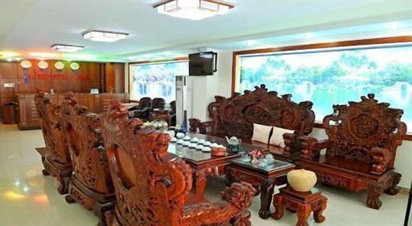 A traditional wooden furniture arrangement with a television and a view of greenery outside.