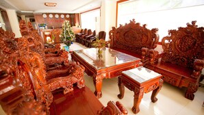 A luxurious room with ornate wooden furniture, including a large sofa and chairs, a glass-top coffee table, and a reception desk in the background. - Binh Phuong Hotel (Ho Chi Minh City)