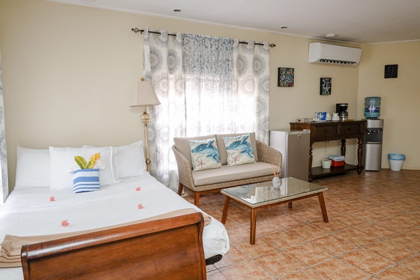 A room with a bed, a sofa, a coffee table, a water dispenser, and a refrigerator.