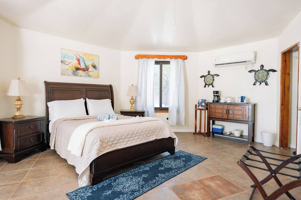 Un dormitorio con cama, mesitas de noche, cómoda, ventana con cortinas y decoración en la pared.