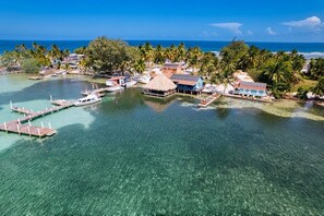 Een tropisch eilandresort met helder water, bungalows op palen en een steiger.