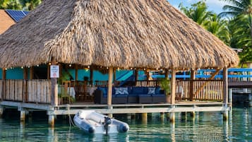 A thatched-roof structure with a pool and lounge area, a no-fishing zone sign, and a small boat.